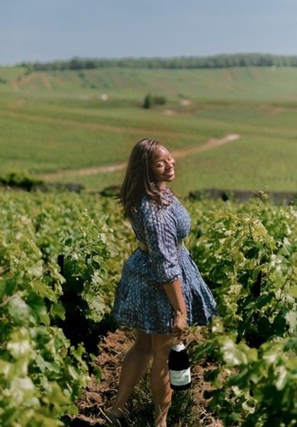 Samantha the owner in a wine field holding a bottle of LoveLUVV Champagne